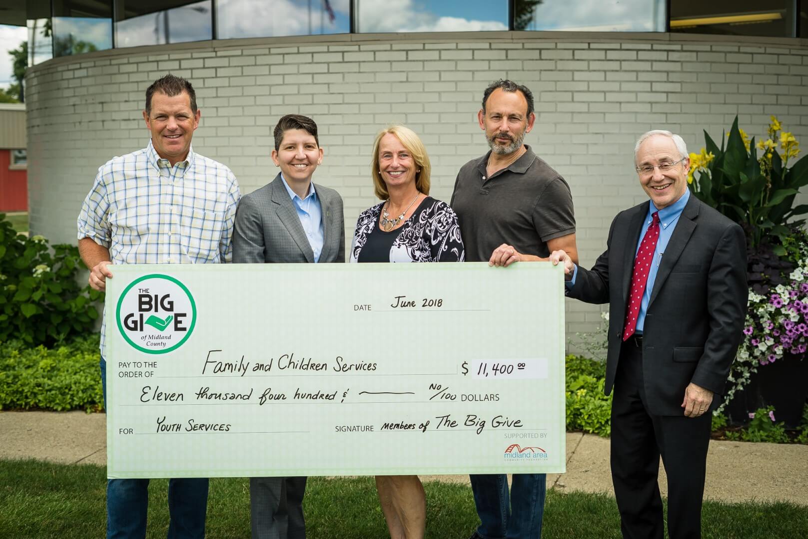Members of The Big Give hand a giant check to Family and Children's Services